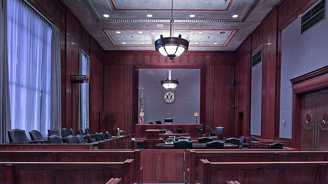Lege rechtszaal met houten panelen, publieksbanken, juryzetels, rechterstoel, hanglampen en een Amerikaanse vlag bij een wandzegel
