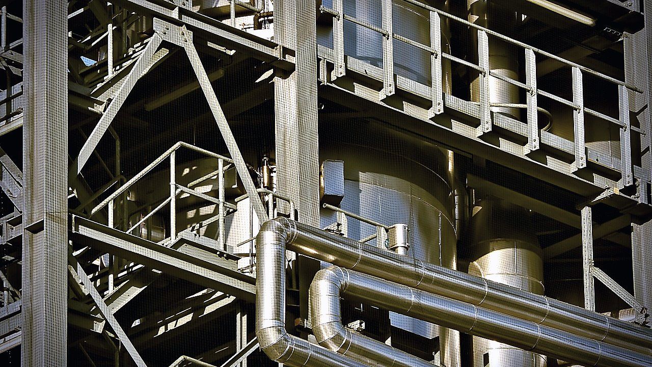 Industriële installatie met stalen frame, trappen, leuningen, glimmende geïsoleerde buizen en grote cilindervormige tanks